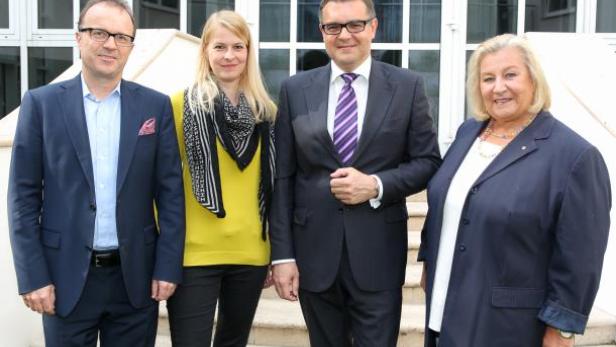 Vier Personen posieren vor einem Gebäude für ein Gruppenfoto.