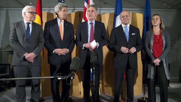 Eine Gruppe von Politikern steht vor Flaggen verschiedener Länder.