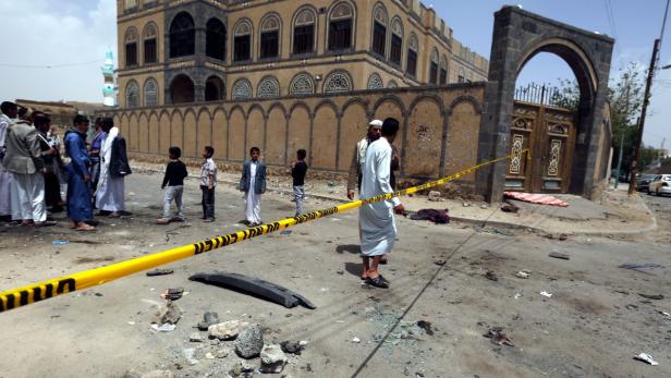 Nach einem Anschlag stehen Menschen hinter einem Absperrband vor einem Gebäude.