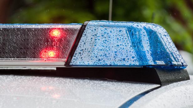 Blaulicht und rote Lichter auf dem Dach eines Einsatzfahrzeugs im Regen.