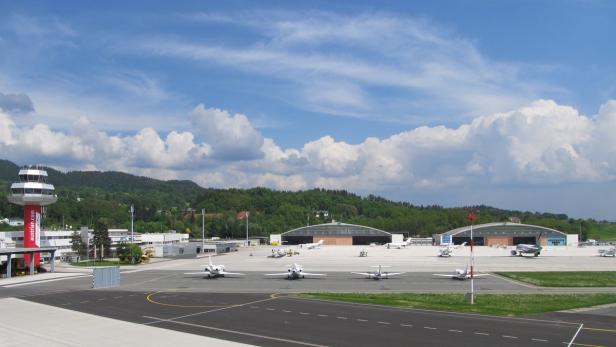Der Flughafen Innsbruck mit Flugzeugen auf dem Rollfeld und dem Kontrollturm im Vordergrund.
