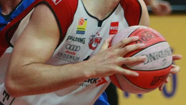 Ein Basketballspieler hält einen Ball der Marke Spalding in den Händen.