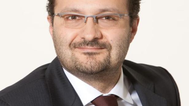 Ein Mann mit Brille, Anzug und Krawatte blickt in die Kamera.
