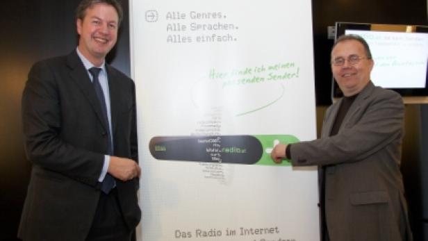 Zwei Männer präsentieren ein Plakat für „radio.at“, das Radio im Internet mit über tausend Sendern.