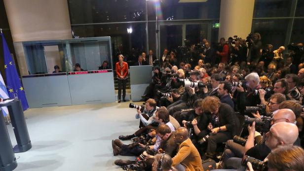 Angela Merkel und ein weiterer Politiker stehen vor einer Wand aus Fotografen.