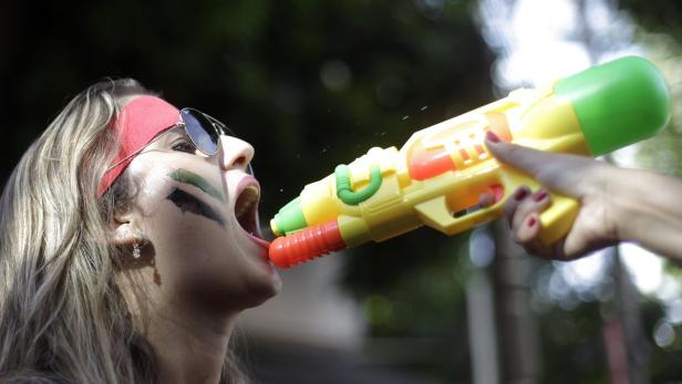 Eine Frau mit Gesichtsbemalung wird mit einer Spielzeugwasserpistole bespritzt.