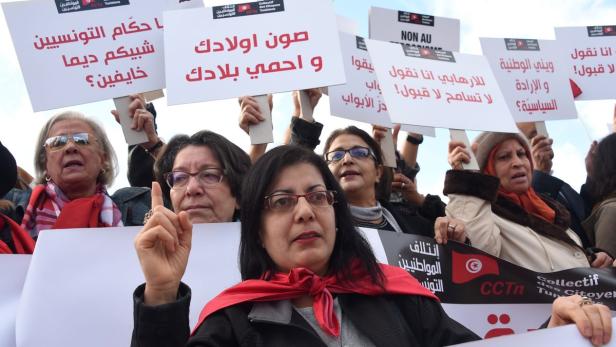 Frauen demonstrieren mit Schildern auf Arabisch und Französisch in Tunesien.