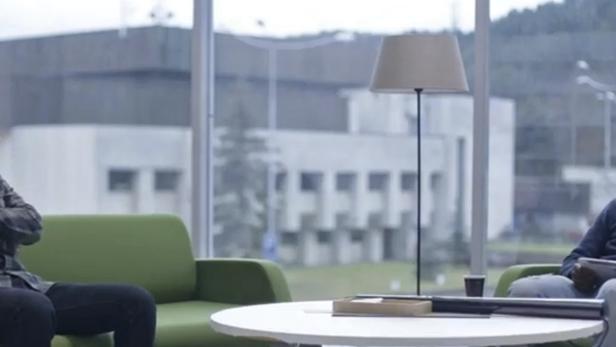 Zwei Männer sitzen in Sesseln und unterhalten sich in einem modernen Büro.
