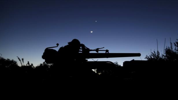 Die Silhouette einer Kanone vor einem Nachthimmel mit Mond und Sternen.