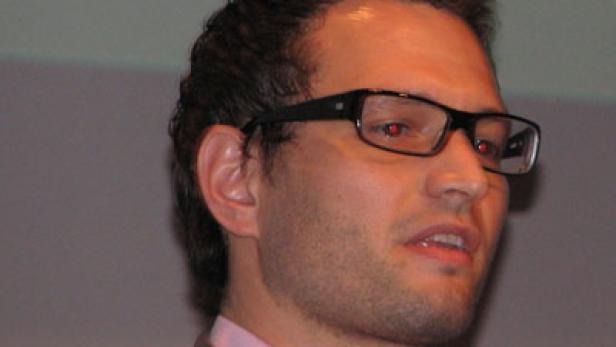 Ein Mann mit Brille und rosa Hemd schaut zur Seite.