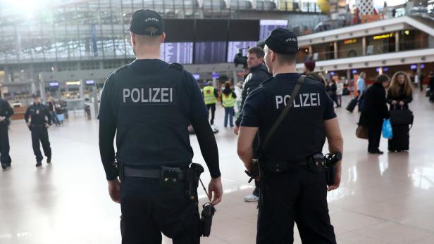 Polizisten patrouillieren in einer Flughafenhalle.