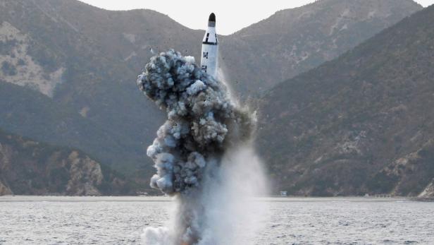 Eine Rakete startet von einer Plattform im Meer, Rauch und Explosion sind sichtbar.