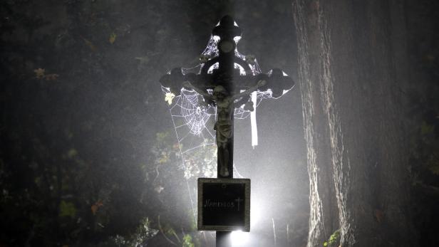 Ein Kreuz mit einer Jesusfigur ist mit Spinnweben bedeckt und trägt die Aufschrift „Namenlos“.