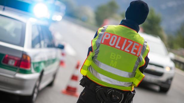 Ein Polizist mit Warnweste steht an einer Straßensperre.