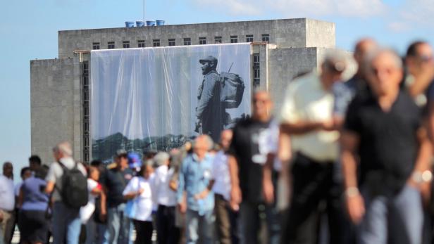 Eine Menschenmenge vor einem Gebäude mit einem großen Porträt von Che Guevara.