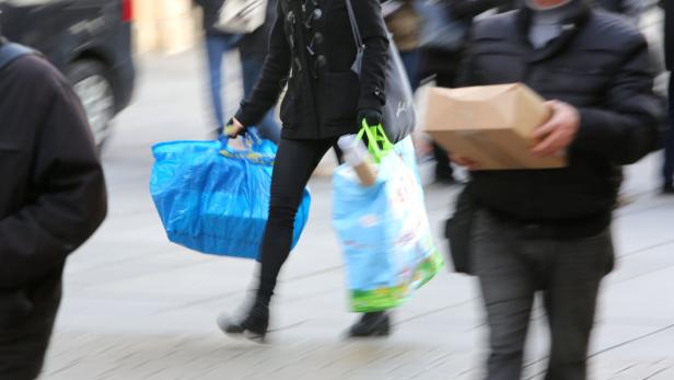 Eine Frau trägt mehrere Einkaufstüten und einen Shopper durch die Fußgängerzone.