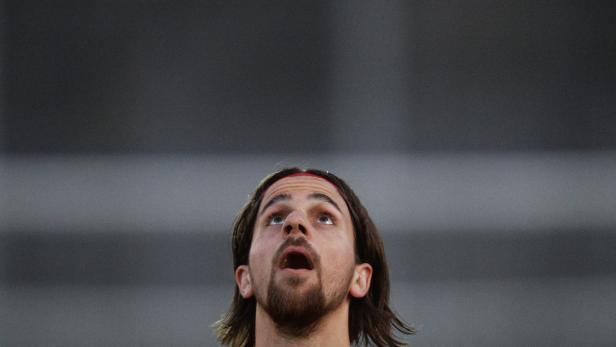 Ein Mann mit Bart und Stirnband blickt nach oben.