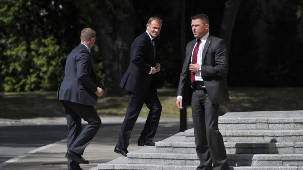 Donald Tusk geht mit zwei Begleitern eine Treppe hinauf.