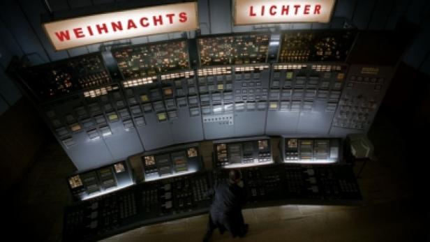 Ein Mann steht vor einer großen Schalttafel mit der Aufschrift „Weihnachts Lichter“.