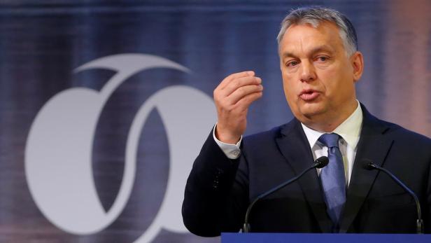 Viktor Orbán spricht vor einem blauen Hintergrund mit einem weißen Logo.