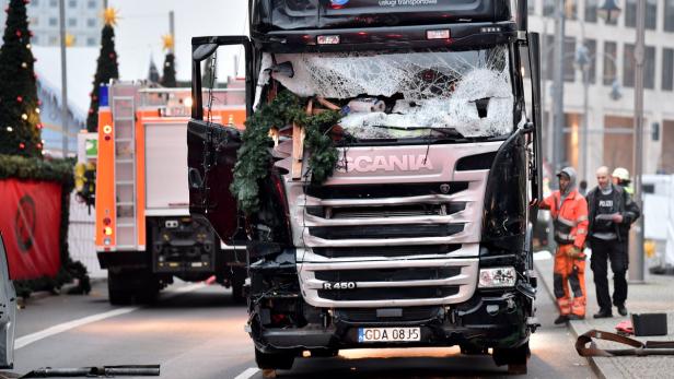 Ein beschädigter Scania-Lkw mit zerbrochener Windschutzscheibe steht auf einer Straße.