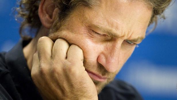 Ein Mann mit Bart stützt sein Gesicht in seine Hand.