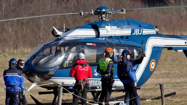 Ein blauer Hubschrauber der Gendarmerie mit Rettungskräften auf einem Feld.