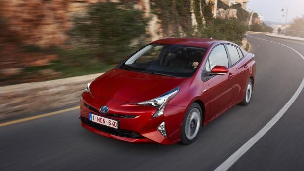 Ein roter Toyota Prius fährt auf einer kurvigen Straße.