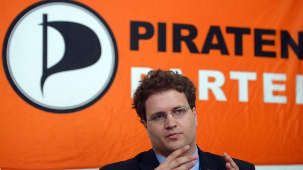 Ein Mann mit Brille vor einem Banner der Piratenpartei.