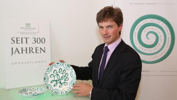 Ein Mann im Anzug präsentiert Geschirr der Gmundner Keramik Manufaktur.