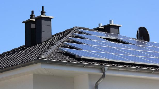 Auf dem Dach eines Hauses befinden sich Solarzellen und Schornsteine.