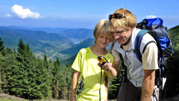Ein Vater und sein Sohn benutzen ein GPS-Gerät beim Wandern in den Bergen.