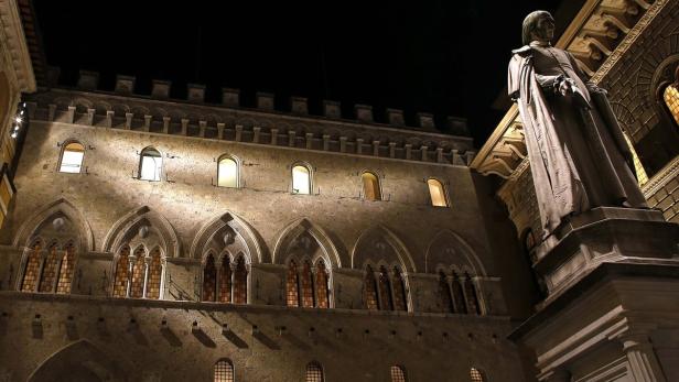Nachts erstrahlt der Palazzo Pubblico in Siena neben einer Statue.