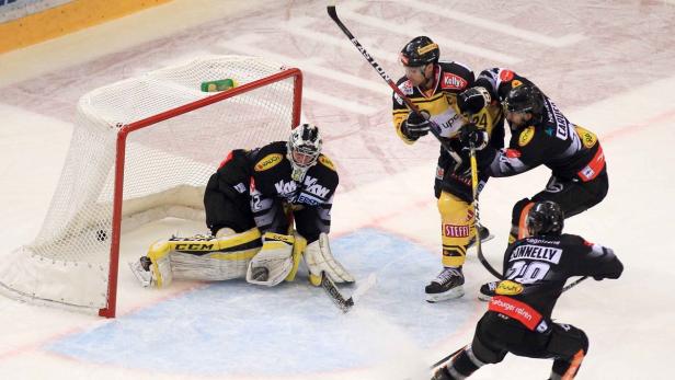 Ein Eishockeyspieler versucht, den Puck ins Tor zu schießen, während der Torwart ihn abzuwehren versucht.