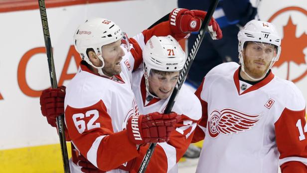 Drei Eishockeyspieler der Detroit Red Wings umarmen sich auf dem Eis.