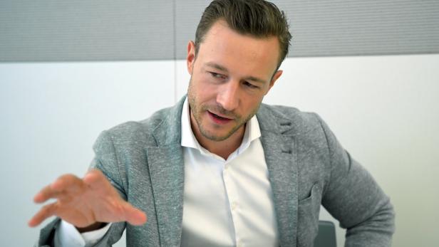 Ein Mann mit grauem Sakko gestikuliert während eines Gesprächs.