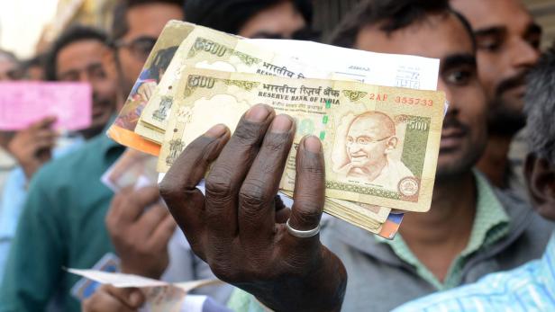 Inder warten in einer Schlange, um Geldscheine umzutauschen.