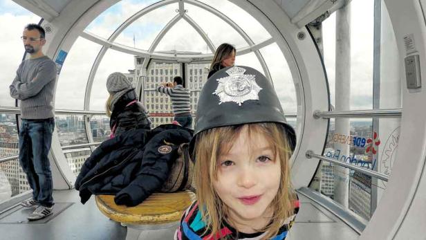 London Eye: Im weißen Riesenrad und mit Bobby-Helm am Kopf macht die Aussicht auf die City mit Westminster Abbey und Big Ben Spaß.