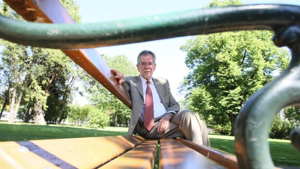 Ein Mann in Anzug sitzt auf einer Parkbank.