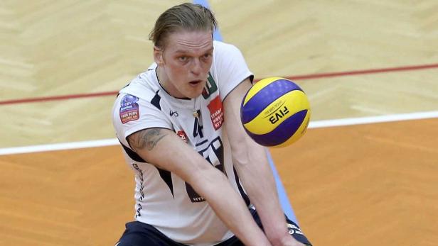 Ein Volleyballspieler baggert einen gelb-blauen Ball.