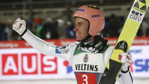 Stefan Kraft feiert mit erhobenem Arm und Skiern in der Hand.