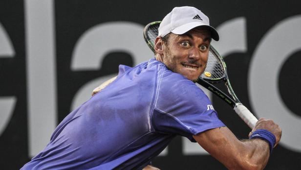 Ein Tennisspieler mit weißer Kappe blickt mit aufgerissenen Augen über seine Schulter.