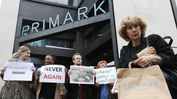 A shopper passes demonstrators outside clothing re Nach dem Einsturz der Textilfabrik kam es weltweit zu Protesten.