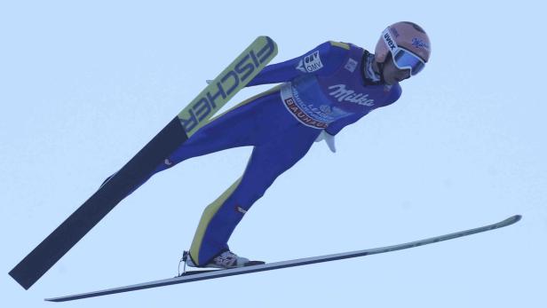 Ein Skispringer in der Luft mit Skiern der Marke Fischer.