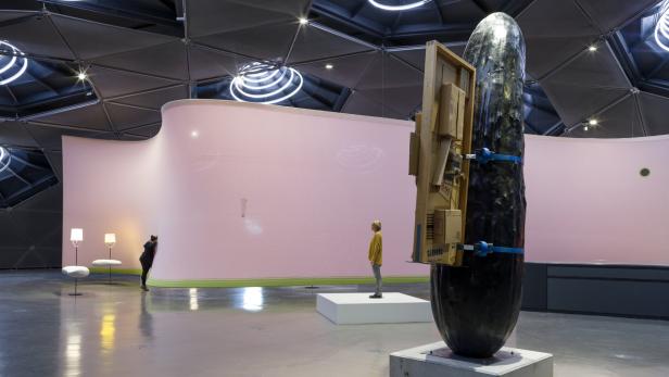 Grazer Kunsthaus: rosaroter „Weltraumschwitzer“ und Riesengurke mit umgeschnallter Rauschenberg-Skulptur von Erwin Wurm