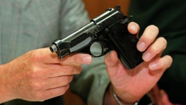 Eine Person hält eine schwarze Beretta-Pistole in der Hand.