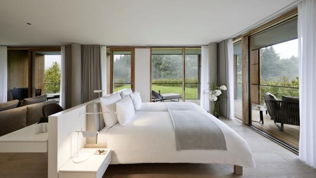 Ein helles Schlafzimmer mit Zugang zu zwei Balkonen mit Blick auf die Natur.