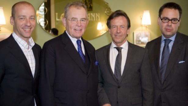 Vier Männer in Anzügen posieren für ein Gruppenfoto.