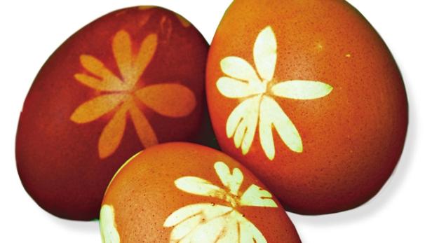 Drei braune Ostereier mit Blumenmuster liegen zusammen.