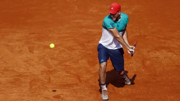 Ein Tennisspieler schlägt auf einem Sandplatz einen Ball.